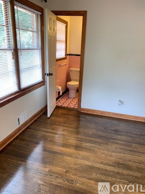 A bathroom with a toilet and a window with blinds.