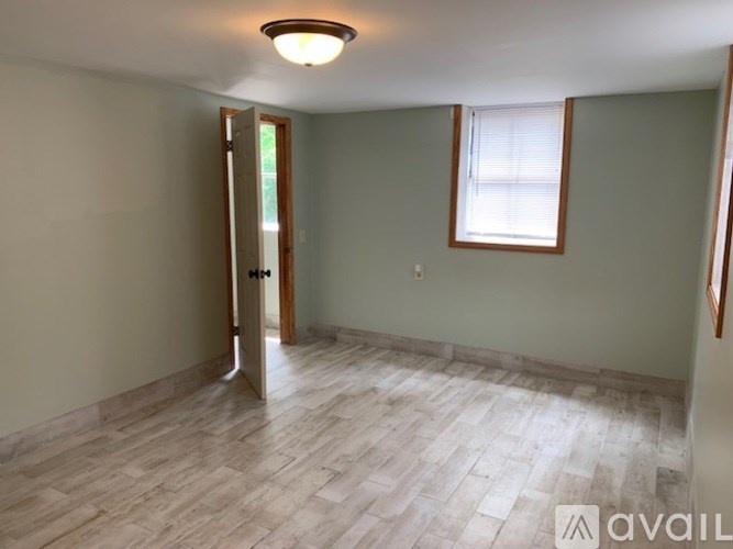 A room with a wooden floor and a window with blinds.