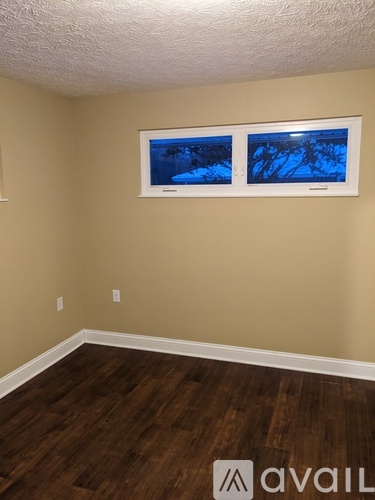 A room with a window showing a blue sky and trees outside.