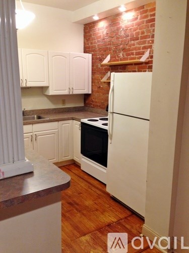 A kitchen with a white refrigerator and wooden floors.