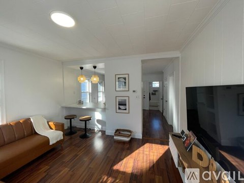 A living room with a brown leather couch and a wooden floor.