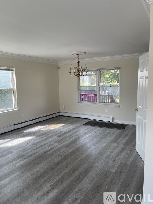 A room with wooden flooring and a chandelier.