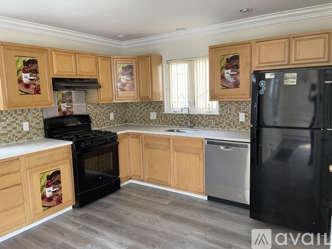 A kitchen with wooden cabinets and a black refrigerator.