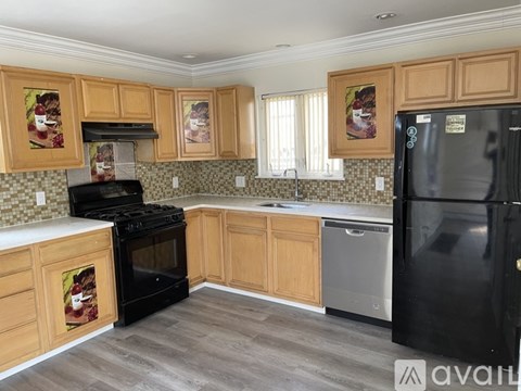A kitchen with wooden cabinets and a black refrigerator.