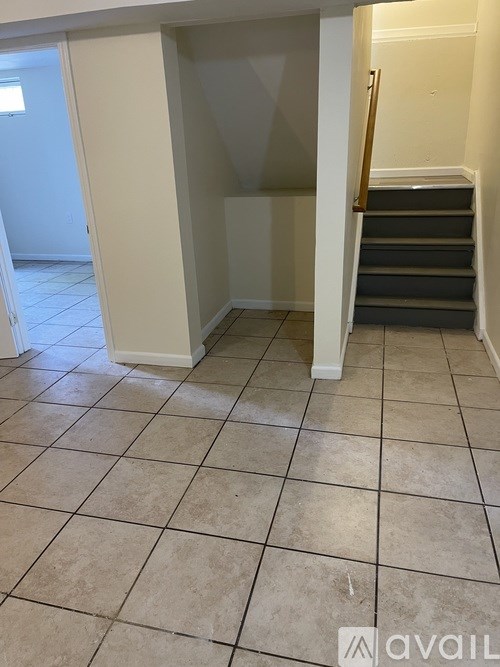 A room with tiled flooring and a staircase.