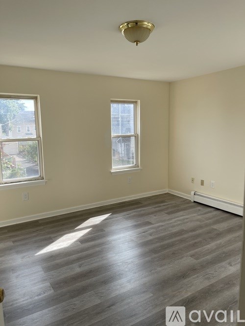 A room with a wooden floor and two windows.