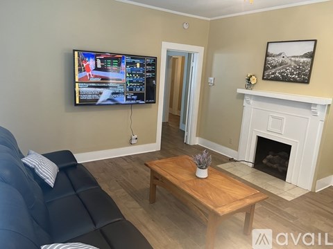 A living room with a blue sofa, a wooden coffee table, a fireplace, and a television displaying a video game.