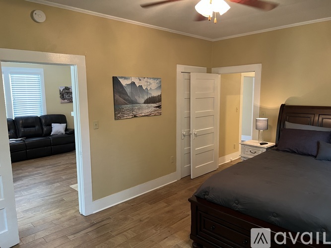 A bedroom with a bed, a couch, and a painting on the wall.