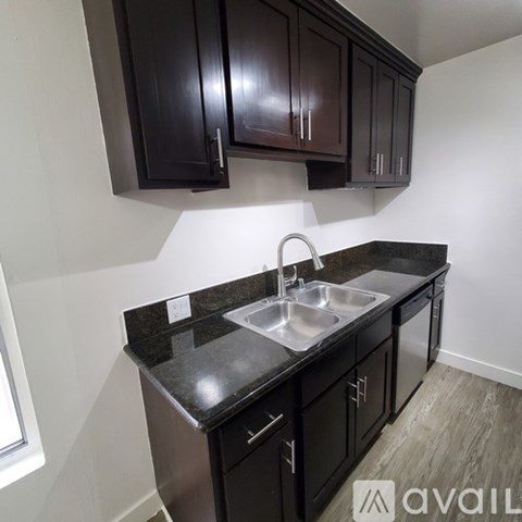 A kitchen with dark brown cabinets and a granite countertop.