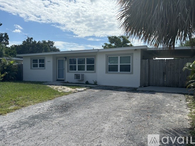 A white house with a gravel driveway in front.