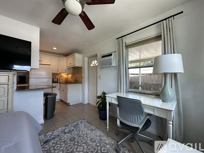 A living room with a grey sofa and a white desk.