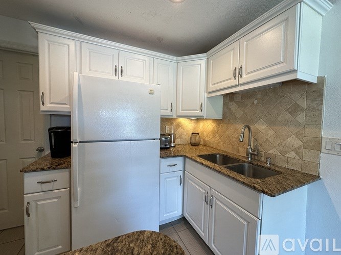 A kitchen with white cabinets and a granite countertop.