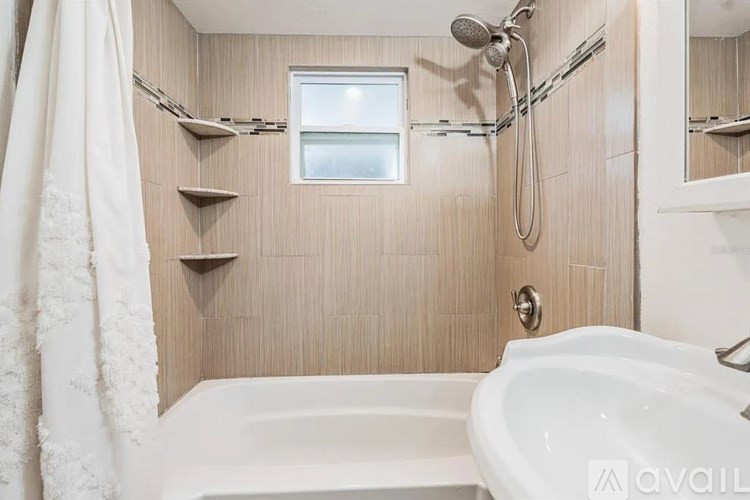 A bathroom with a white tub and a window with a curtain.