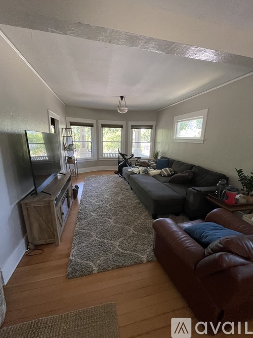 A living room with a brown leather couch and a rug.