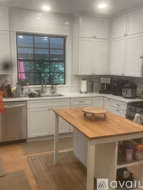 A kitchen with white cabinets and a wooden island.