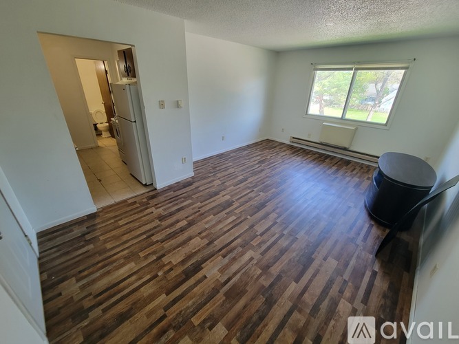 A room with wooden flooring and a window with blinds.