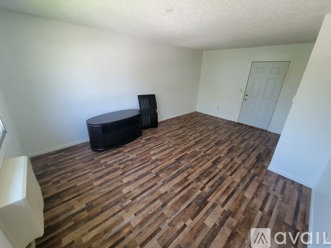 A room with wooden flooring and a black ottoman.