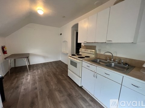 A kitchen with white cabinets and a wooden floor.