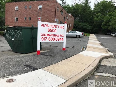 A real estate sign for Aliya Realty LLC is placed on the sidewalk.