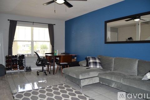 A living room with a grey couch and a blue wall.