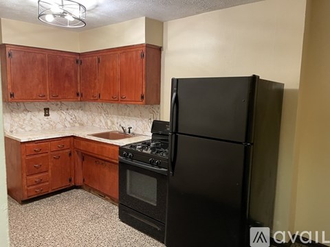 A kitchen with black appliances and wooden cabinets.