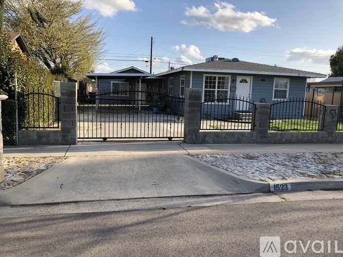 A blue house with a black gate and a sign that reads "1523" in front of it.