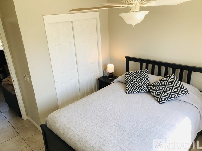 A bedroom with a bed, pillows, and a ceiling fan.