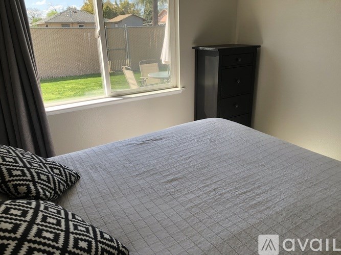 A bedroom with a bed, a window, and a dresser.