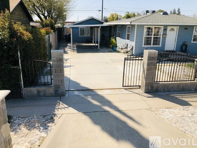 A sunny day in a residential area with houses and a gated driveway.