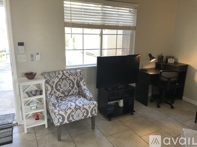 A living room with a chair, a television, and a desk.