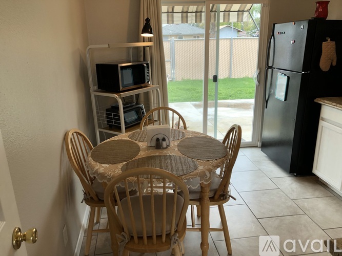 A kitchen with a table and chairs in the foreground and a refrigerator in the background.