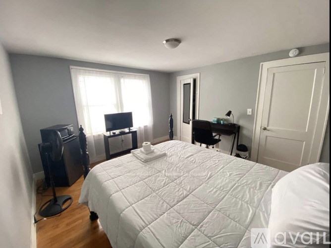 A bedroom with a bed, a desk, and a window.