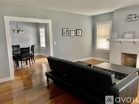A living room with a black couch and a fireplace.