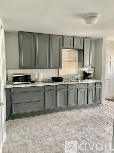A kitchen with grey cabinets and a white countertop.