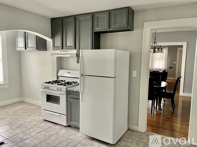 A white refrigerator and stove in a kitchen with grey cabinets.