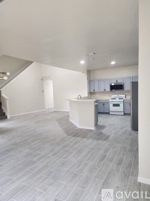 A spacious kitchen with a white island and grey flooring.