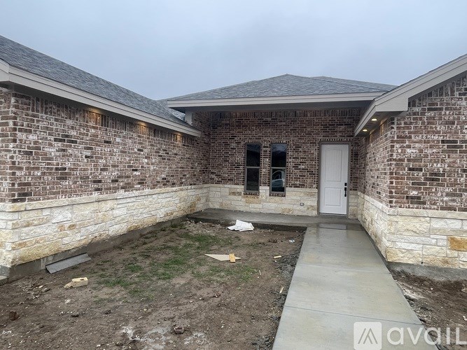 A house under construction with a grey concrete walkway.