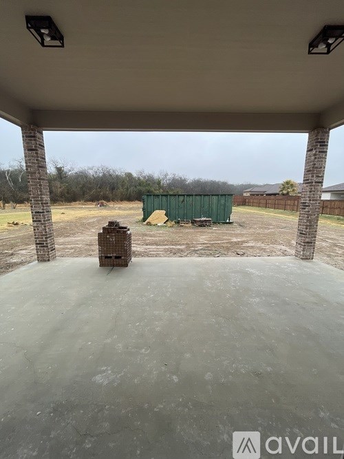 A concrete patio with a green container in the background.