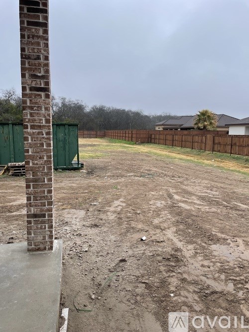 A construction site with a brick pillar and a wooden fence in the background.
