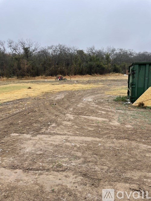 A dirt field with a green container on the right side.