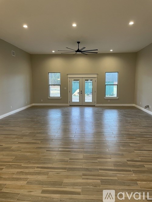 A spacious room with a wooden floor and a ceiling fan.