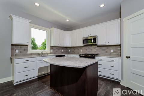 A kitchen with white cabinets and a dark island.
