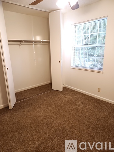 A small bedroom with a window and a white door.