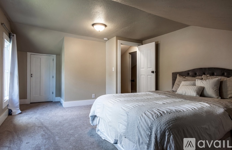 A bedroom with a large bed and a window with curtains.