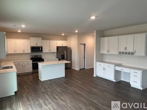 A spacious kitchen with white cabinets and a wooden floor.