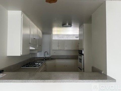 A kitchen with white cabinets and a marble countertop.