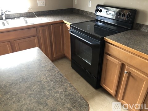 A black oven with a digital display is in a kitchen with wooden cabinets.