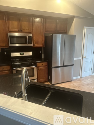 A kitchen with a stainless steel refrigerator and wooden cabinets.