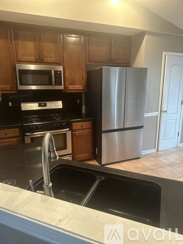 A kitchen with a stainless steel refrigerator and wooden cabinets.