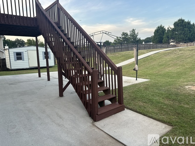 A wooden staircase with a metal railing is in the foreground of a grassy area.